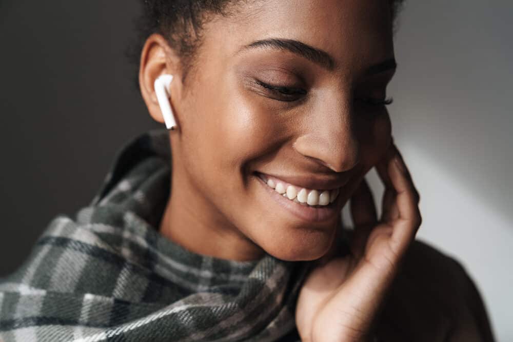 Cute black female with a great smile listening to a podcast about using a benzoyl peroxide product on her skin.