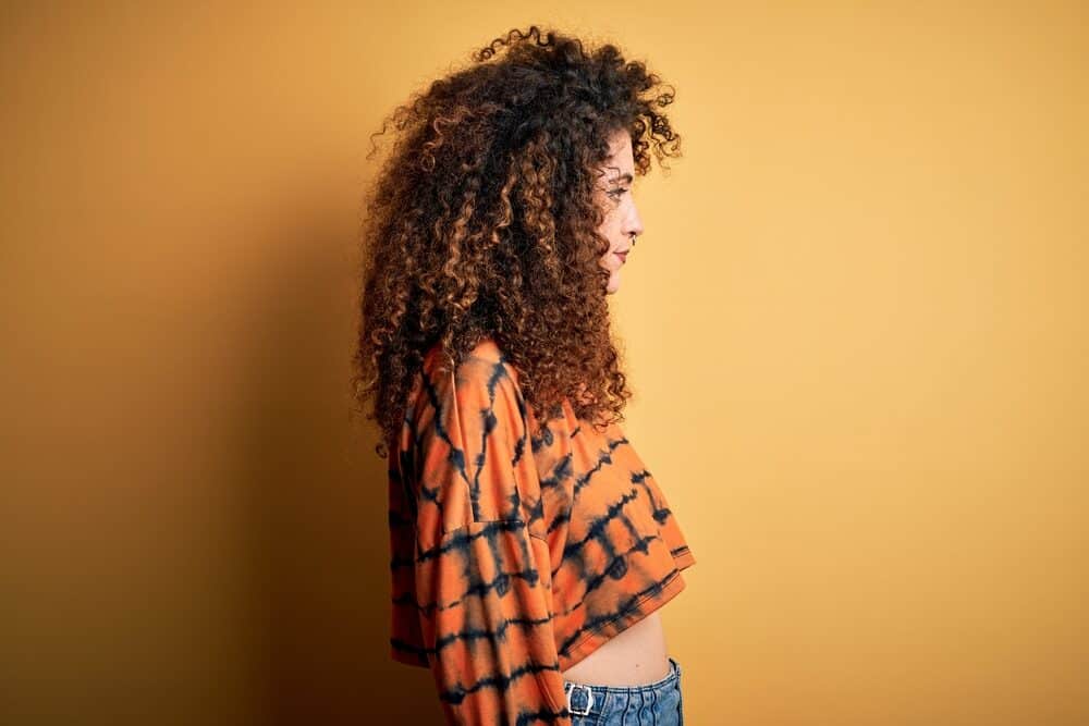 Cute adult female with natural curls enhanced using traditional white girl hair weaving techniques.