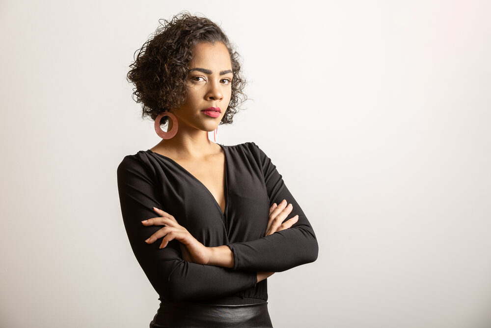 Confident professional female wearing 3B naturally curly hair with her arms folded.