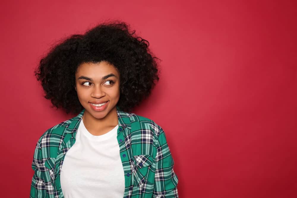 A young African American woman wearing a green and blue flannel shirt with henna hair dye from the henna tree.