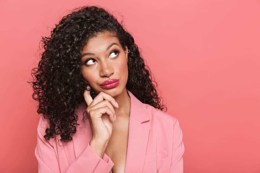 Pensive woman wearing a business suit with a wash and go hairstyle on thick hair that's been dyed dark brown.