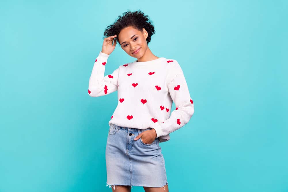 Black woman with mixed L'oreal Feria colours on 4B natural curls wearing a white sweater and a jean skirt.