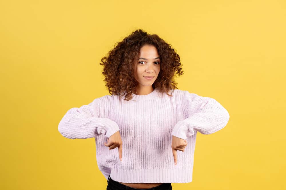 Woman pointing down with fingers wearing a fluffy sweater with 3B natural curls.