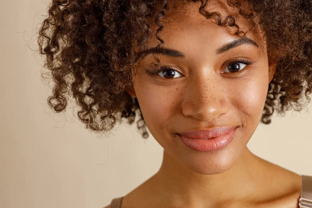 Young African American girl with freckles on her nose wearing curly 3C natural hair.