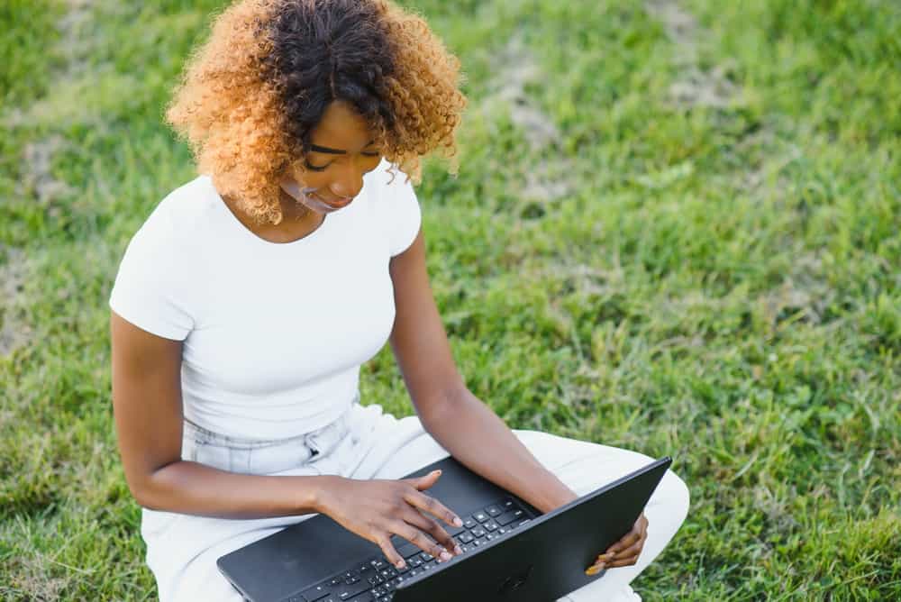 Charming African woman with 4A thick hair dyed by a hair colorist wearing a white t-shirt and jeans.