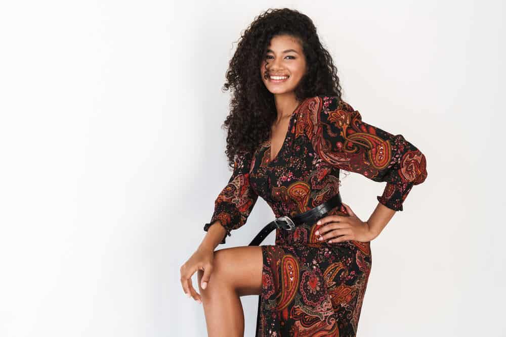 Confident black girl with her hand on her hip with dark brown natural hair wearing a black belt on a colorful dress.