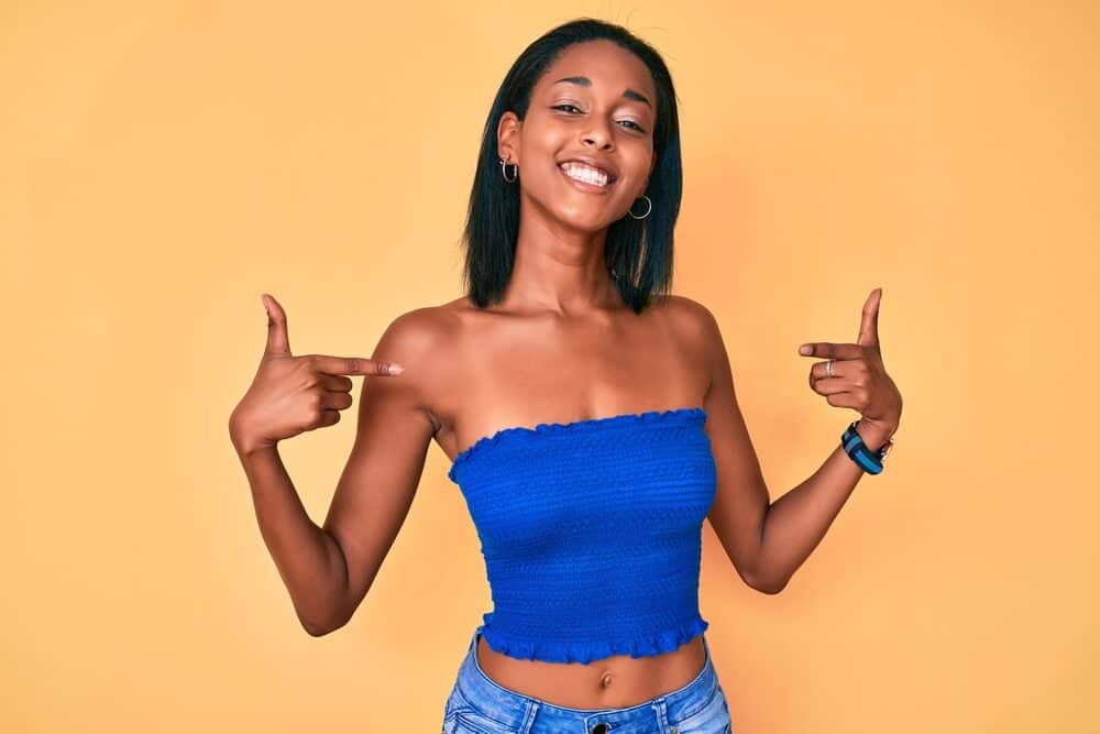 Young African American woman with brittle hair wearing a blue crop top and jeans.