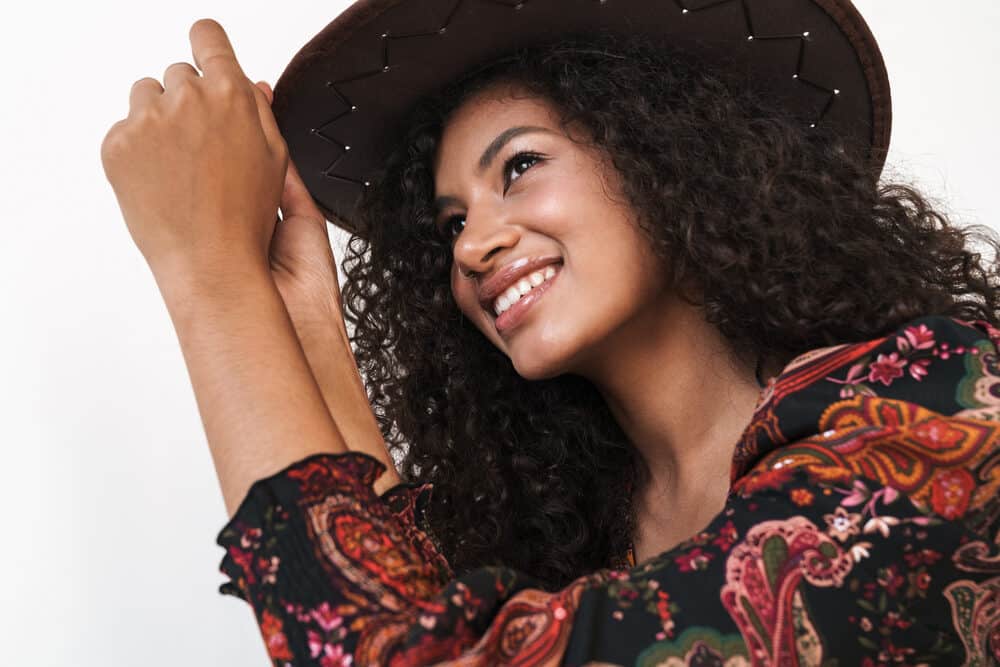 Cheerful black woman wearing a hat to cover her 3B natural hair after having her hair braided in box braids.