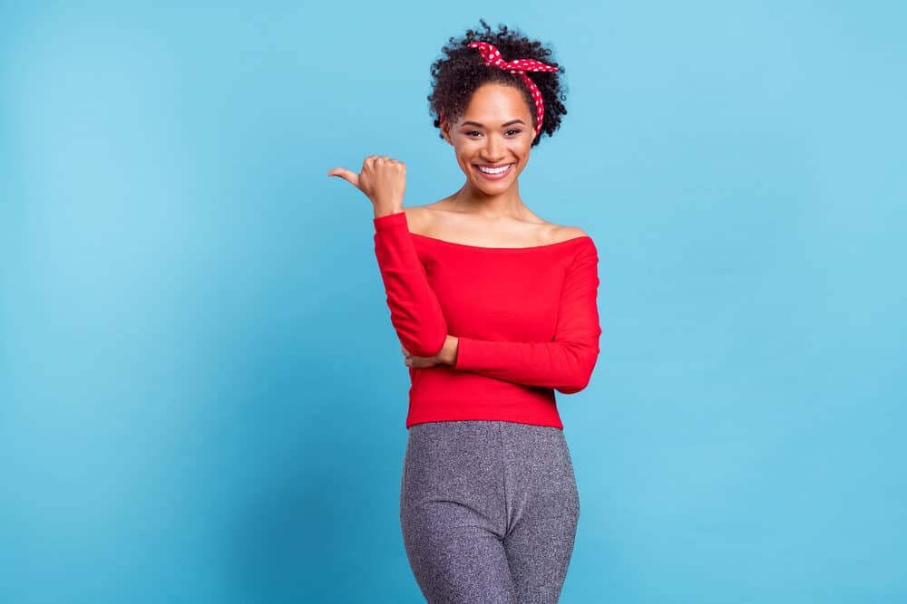 Cute African American female with a 3B hair type wearing a red shirt and gray pants.