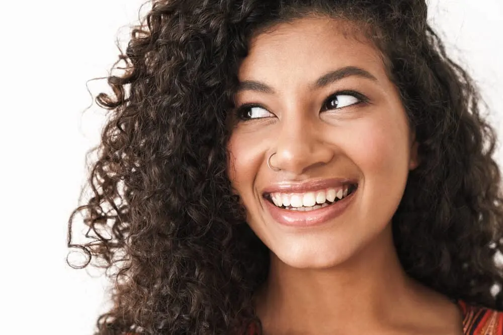 A cute mixed-race girl with long natural hair growth wearing a nose ring and rose lipstick.