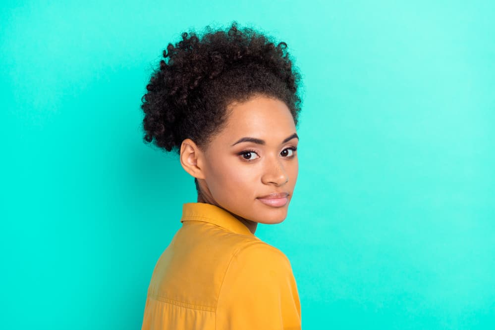 An attractive African American female with healthy hair wearing natural make-up and a yellow dress shirt.