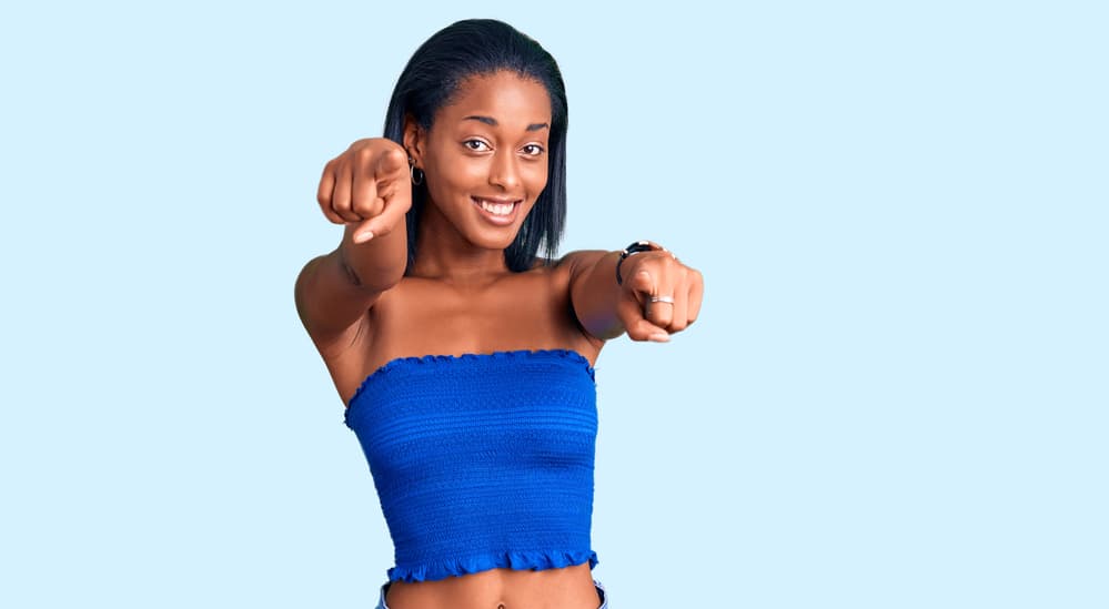 Black woman pointing at the camera with hair damaged from using hot styling tools.