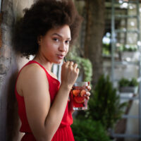 African American female with thicker hair than many 4B curl patterns wearing a red dress while drinking tea.