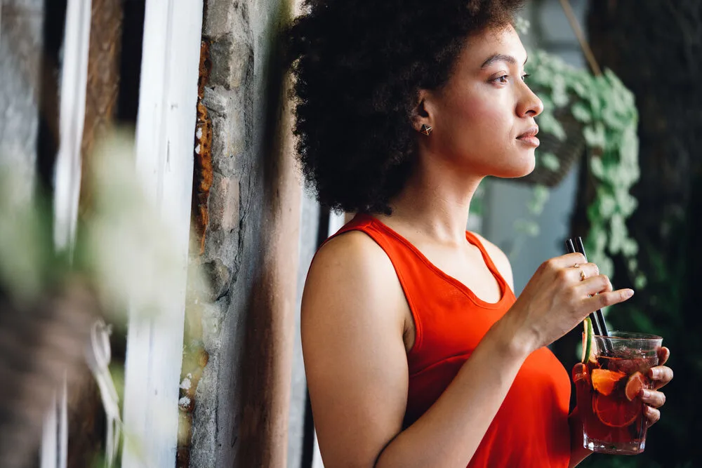 Cute black woman with light brown skin and 4B scalp hair wearing a red dress and gold earrings.