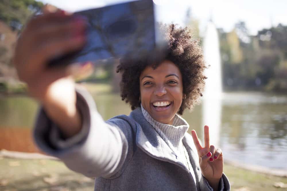 A woman with a great smile and naturally curly twist-out hairdo created virgin coconut oil from fresh coconut meat.