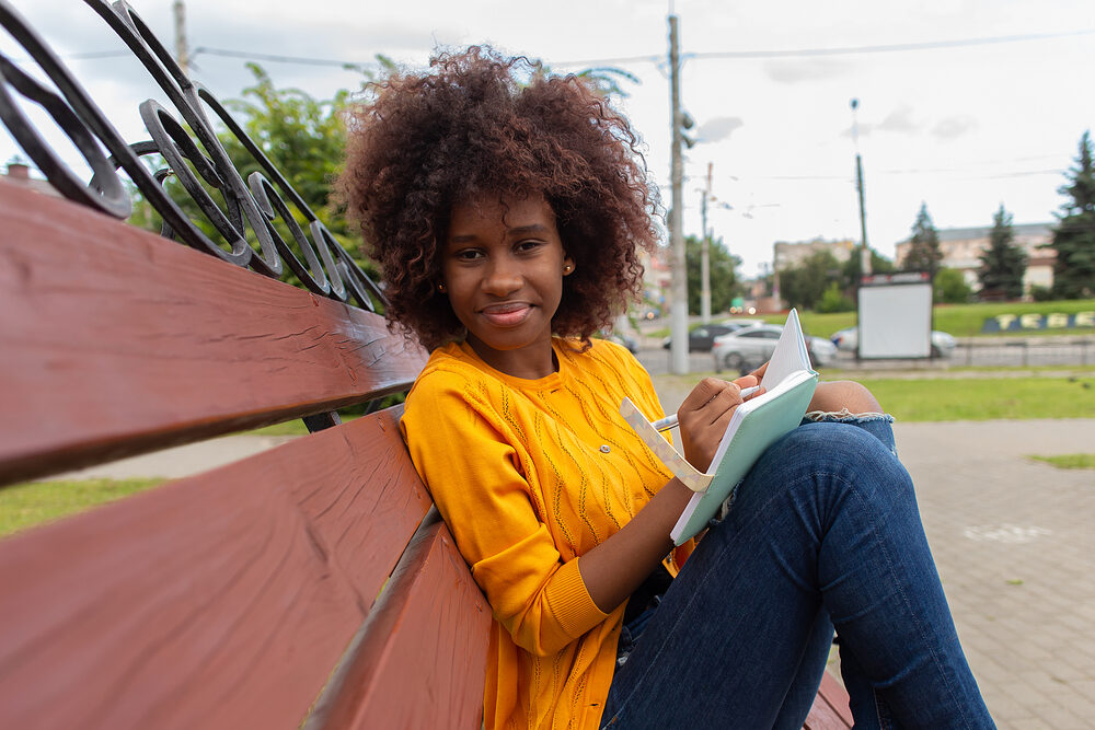 African American woman in the park with hair damaged from using heated tools.