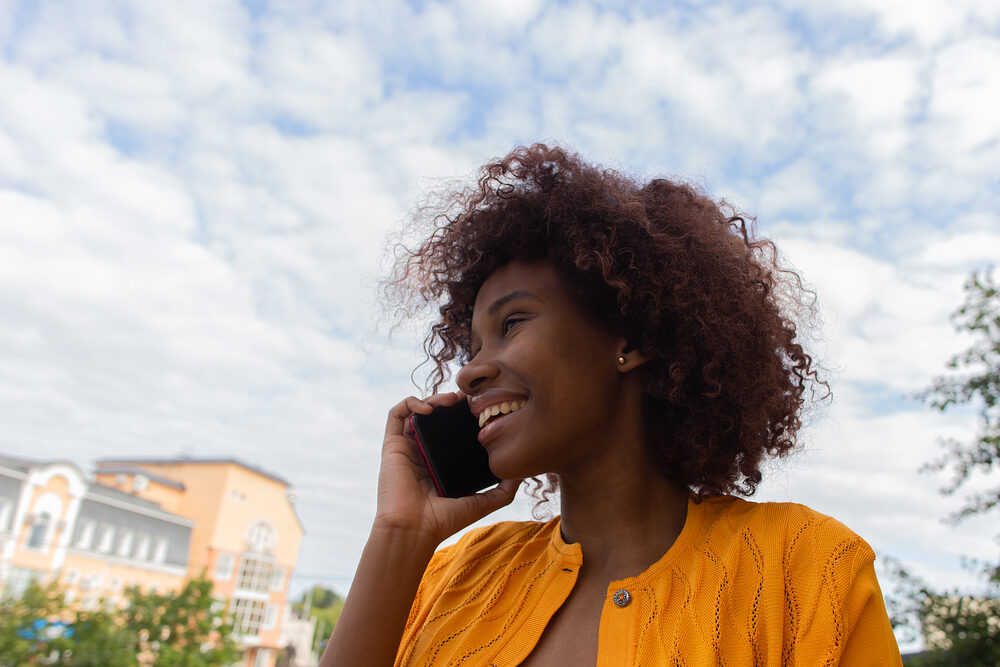 Beautiful lady with heat damage on her 4B hair type talking on the phone with a friend.