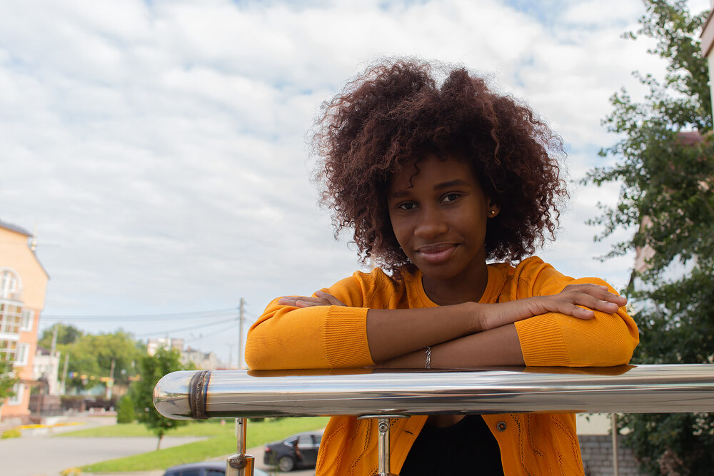 Black girl with signs of hair damage due to excessive heat styling tools without using a heat protectant.