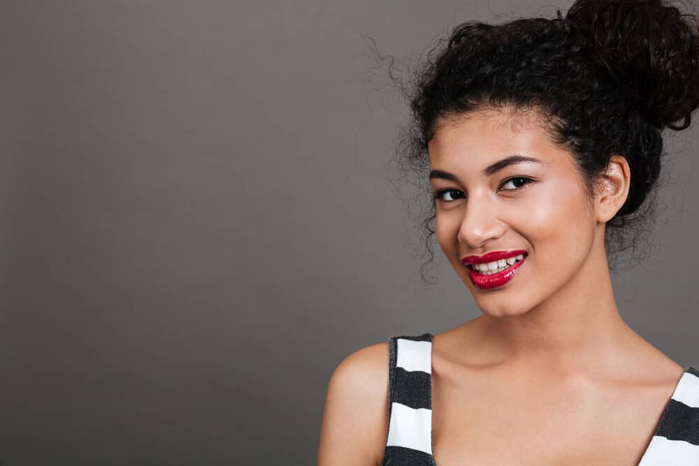 Cute black female with healthy hair in an updo style wearing natural-looking make-up and red lipstick.