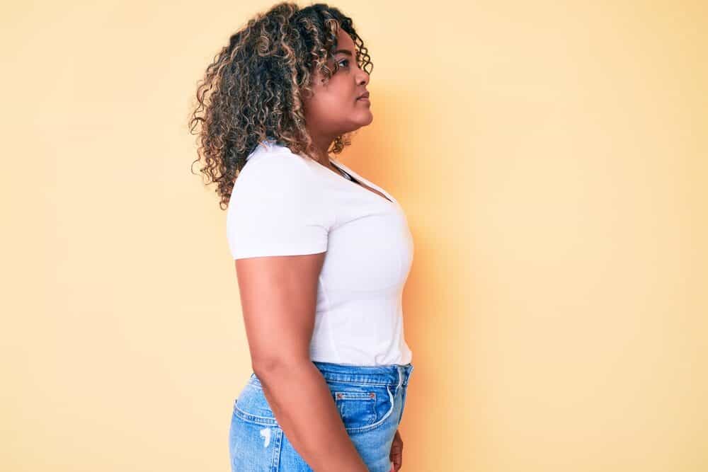 African American female with light brown natural color wearing a white t-shirt and blue jeans.