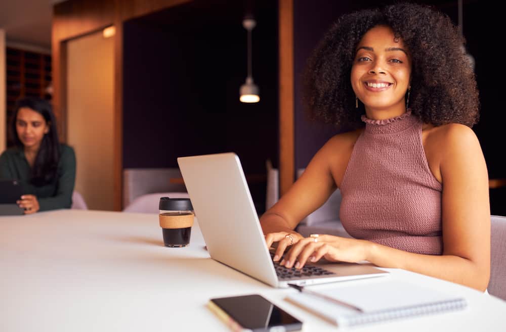 African American woman with black hair wearing a purple shirt researching "grey hair" on her laptop.