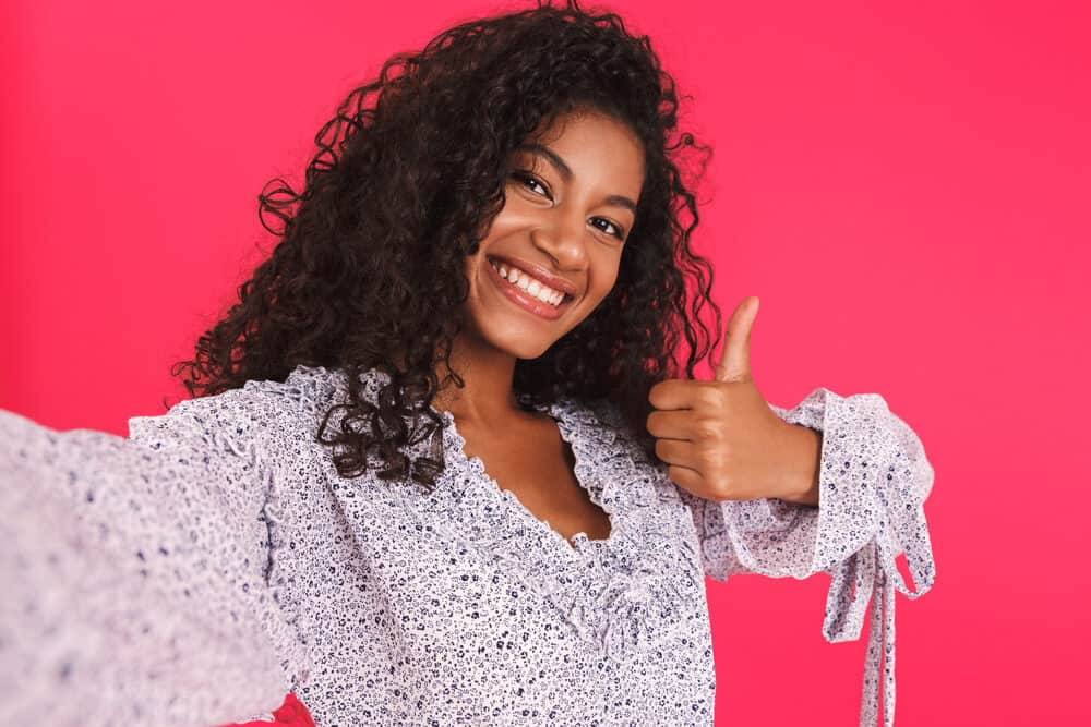 Satisified young female giving a thumbs sign after using the Dyson Airwrap to curl hair without extreme heat.