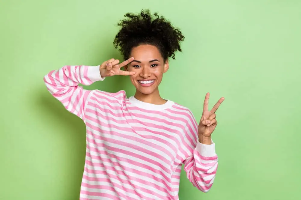Can You Leave Olaplex 3 on Overnight or Leave It on Too Long? 10 African American female dressed in a pink pullover with compromised hair and split-ends from dyeing her curls.