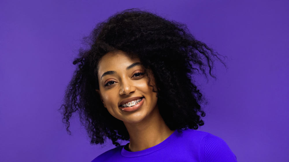 Cute African American female with curly hair cuticles on a jet black hair color styled with an olive oil treatment.