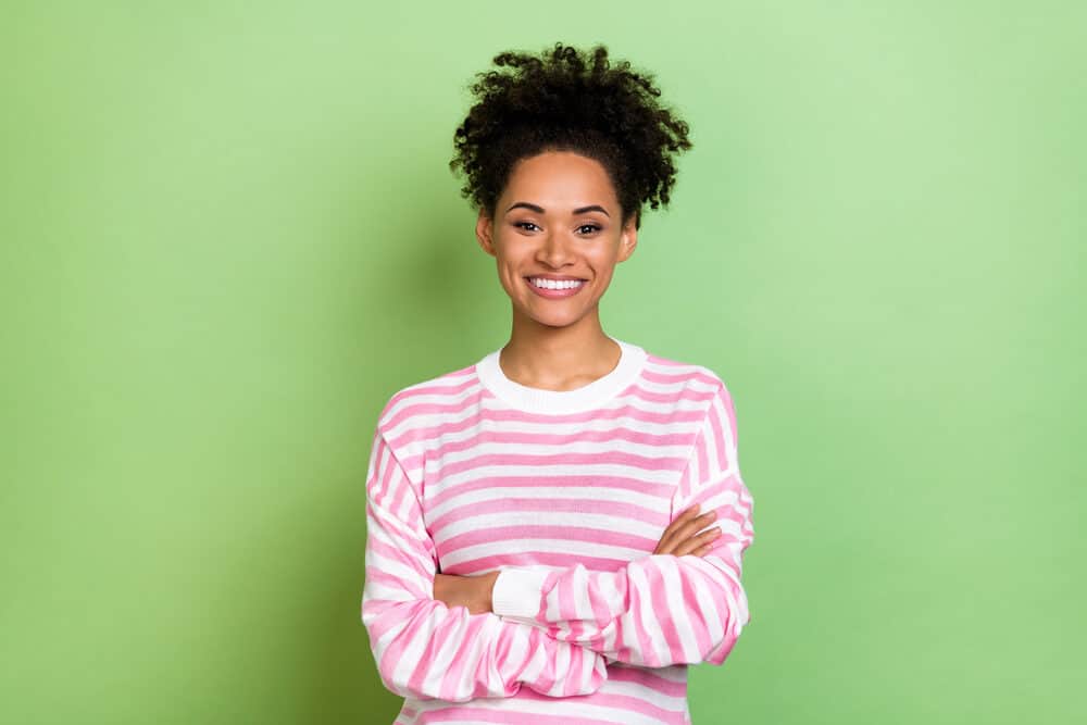 Cute African American female with color-treated hair follicles on 3C healthy hair after a salon treatment.