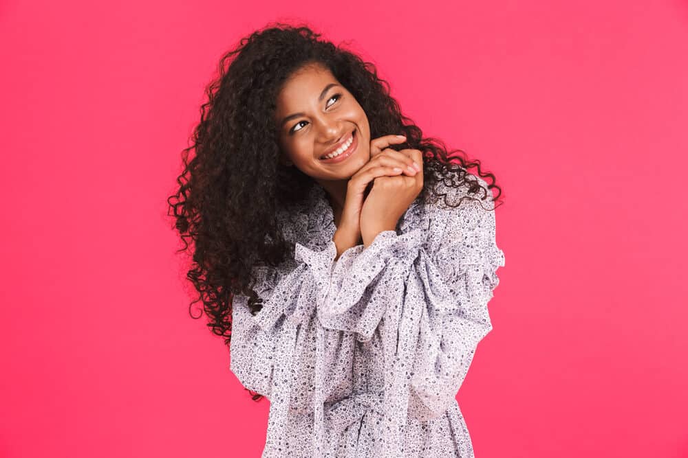 Adult female wearing a pretty dress with long natural curls styled with a soft smoothing brush and blow dryer.