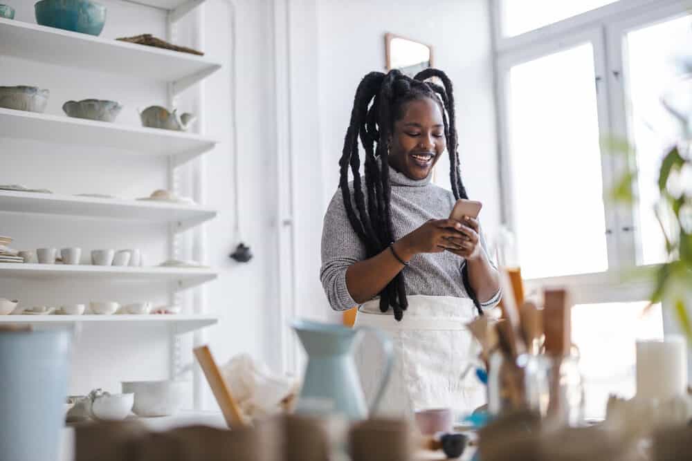 An African American woman with thick freeform dreads reading an article about Congos on her mobile phone.