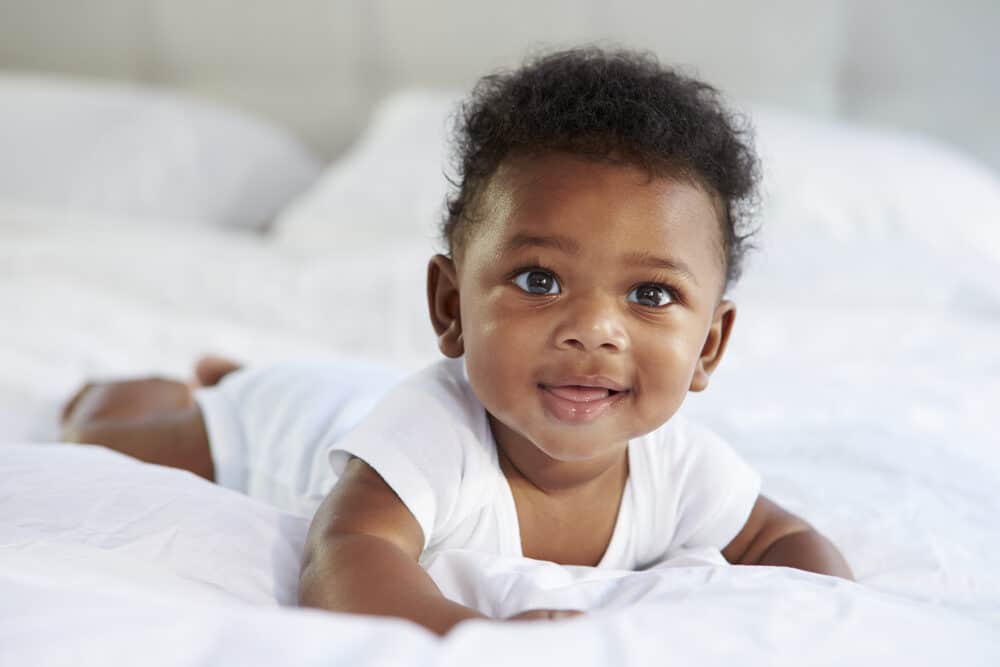 Cute baby girl born with hair during the fetal development process and peach fuzz on her arms, back, and legs.