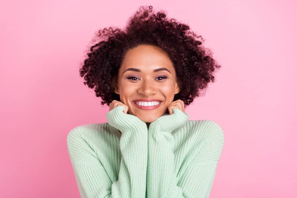 Cute African American female with caramel skin that uses biotin supplements to promote hair growth.