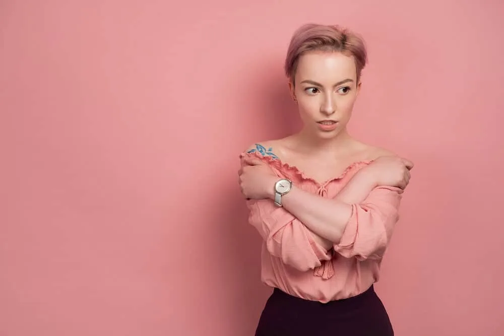 Can White People Get Waves? How Long Does It Take? 4 A pretty female with pink hair and a tattoo on her right shoulder wears a blouse and a silver watch.