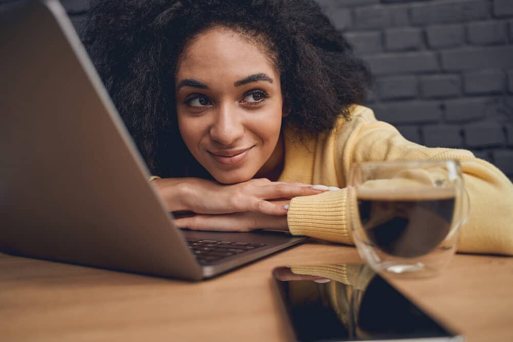 Female with a 4A hair type drinking coffee and wearing a wash n go hairdo after having her hair dyed.