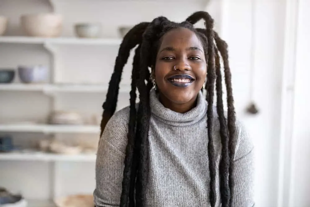 How to Get Congo Dreads: Freeform, Crochet, Interlock, and More 1 African American female with semi-freeform dreads wearing a gray sweater and black lipstick.