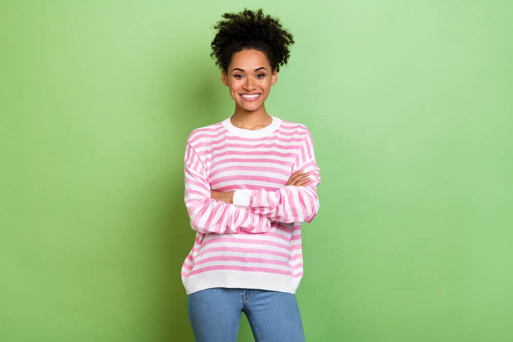 Cute black woman with a curly hair structure wearing casual clothes with her arms folded.