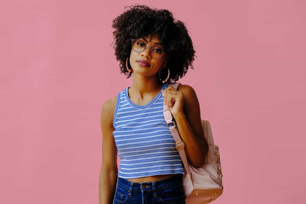 Pretty lady with coily hair strands wearing a comfortable outfit before going shopping.