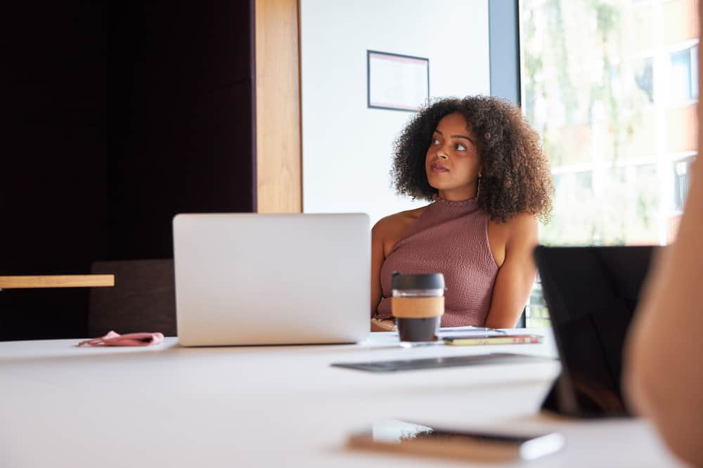 Cute black girl with 3A hair with pastel shades in a business meeting with colleagues.