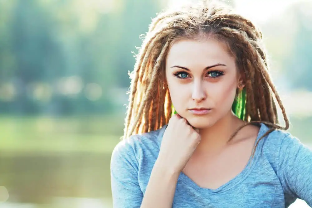 A cute white woman wearing dreadlocks hair with a casual blue t-shirt with blue eyes and make-up.
