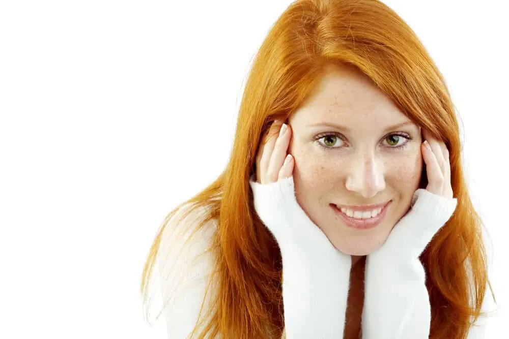 What Color Covers Orange Hair? Brassy? Dye? After Stripping? 10 A lady with 1C straight hair wearing bright orange hair after with her hands on her face.