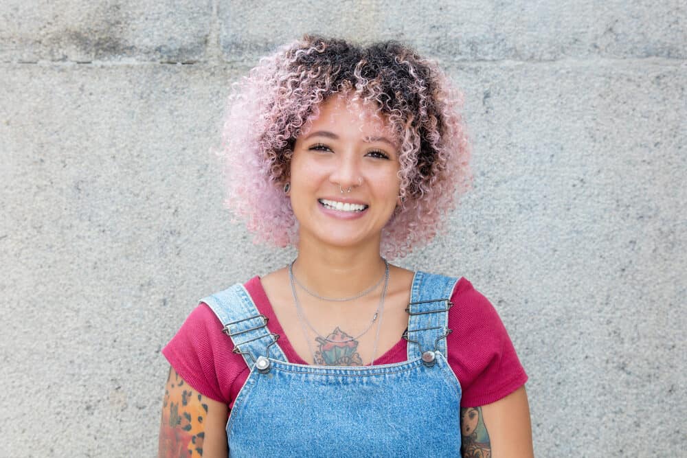 Cute African American female with dark brown natural hair wearing pink temporary hair dye on her 3C curls.