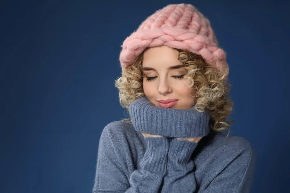 Cute Caucasian female with virgin hair wearing a blue winter outfit with a pink winter hat.