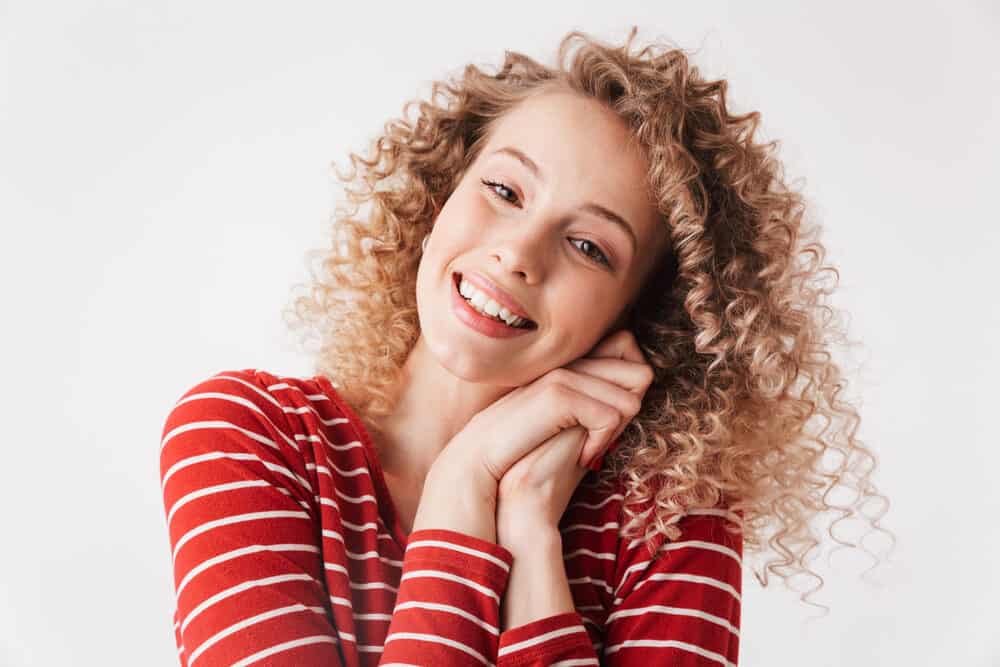 A lady with newly permed hair wearing her tight curls after drying her hair with a microfiber towel.