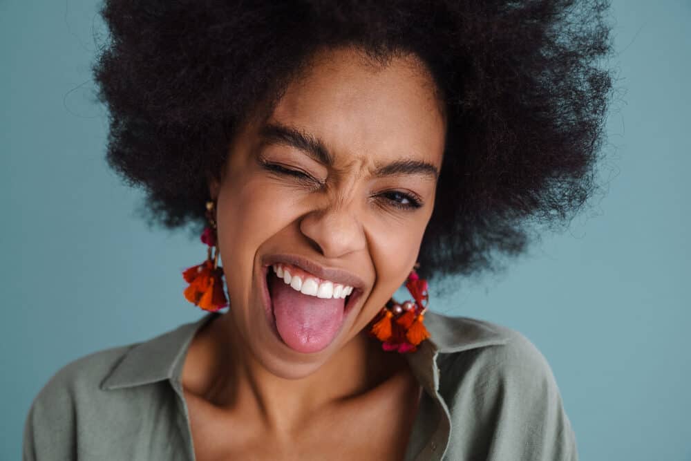 African American girl with natural black hair is sticking her tongue out making a funny face.