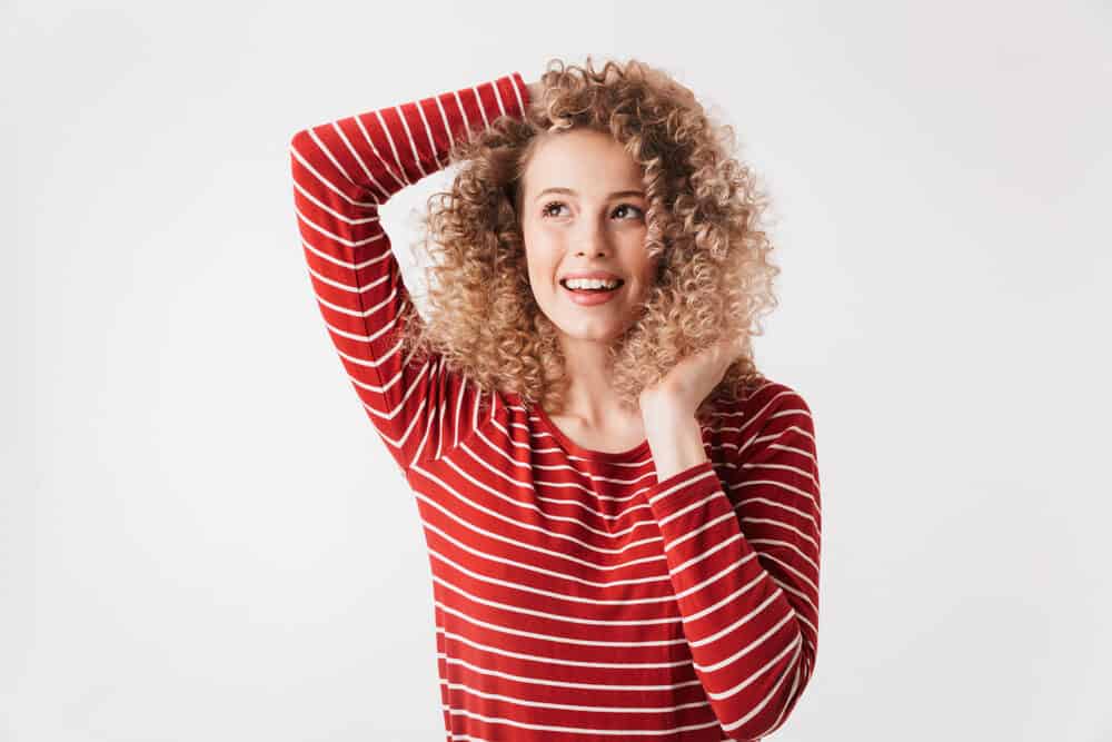 Cute woman with blonde hair wearing spiral curls and tight ringlets keeping her naturally straight hair healthy.