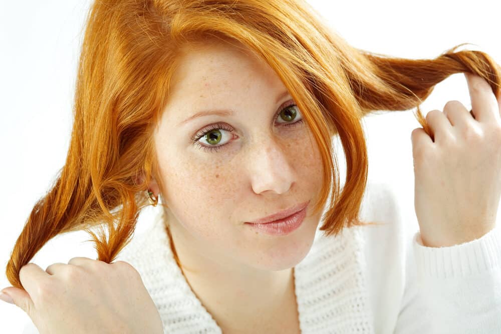 Pretty Caucasian female with a light brown color hair wearing pink lipstick and gold earrings.