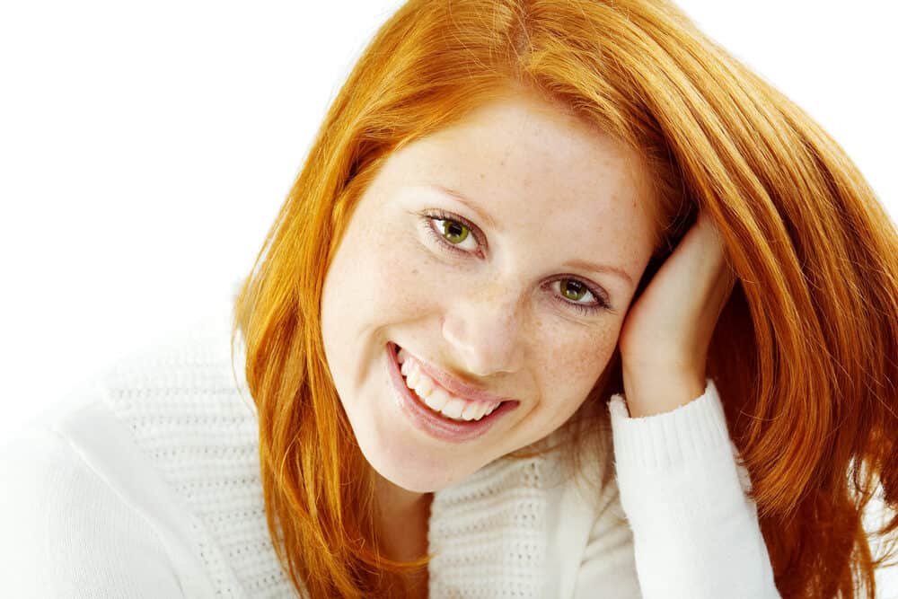 Cute redhead female wearing orange hair with a white wool sweater.