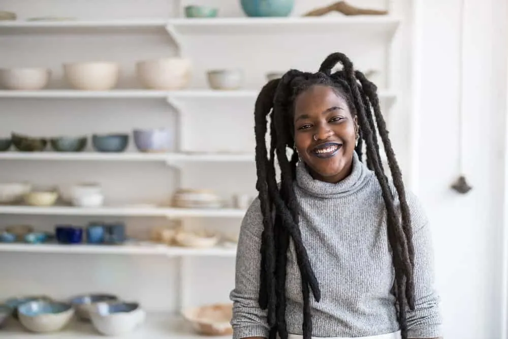 How to Get Congo Dreads: Freeform, Crochet, Interlock, and More 2 Black lady wearing thick freeform locs on a 4C hair type with a nose rise and casual turtle neck sweater.