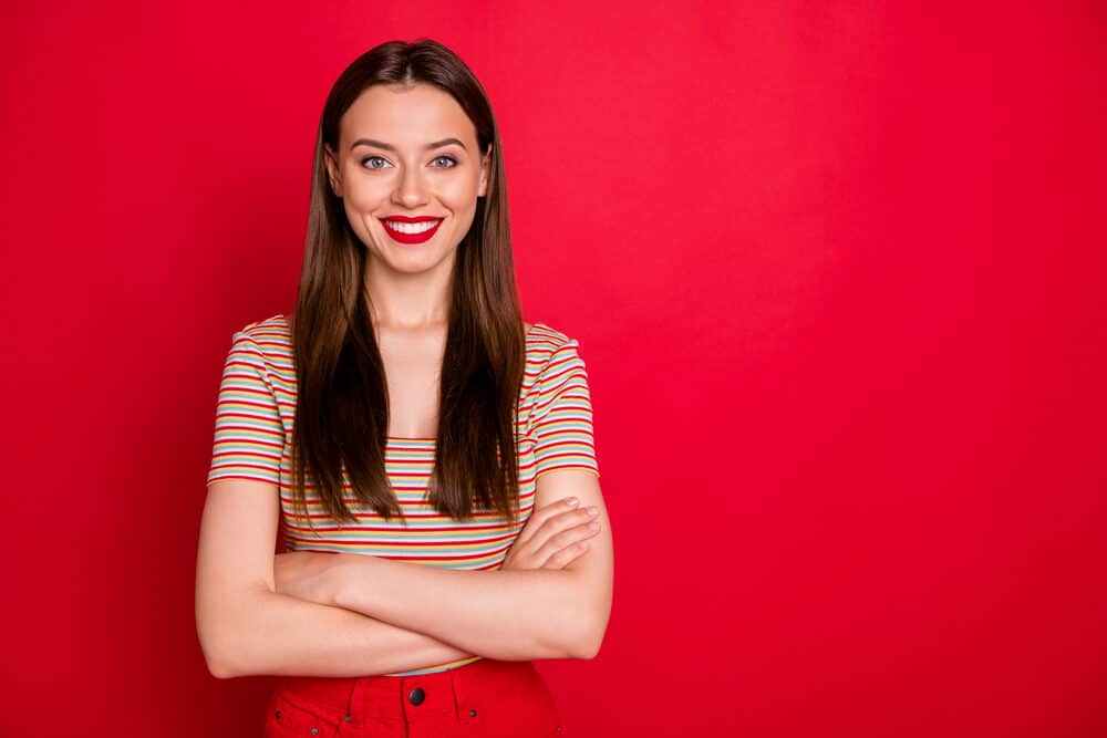 Caucasian female without a curl pattern has a straight hair type after using heat styling tools for a bone straight look.